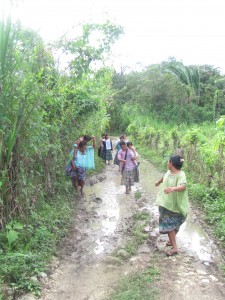 Mayan women walking down a muddy path