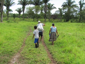 Family walking down muddy path to village