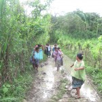 Mayan women walking down a muddy path