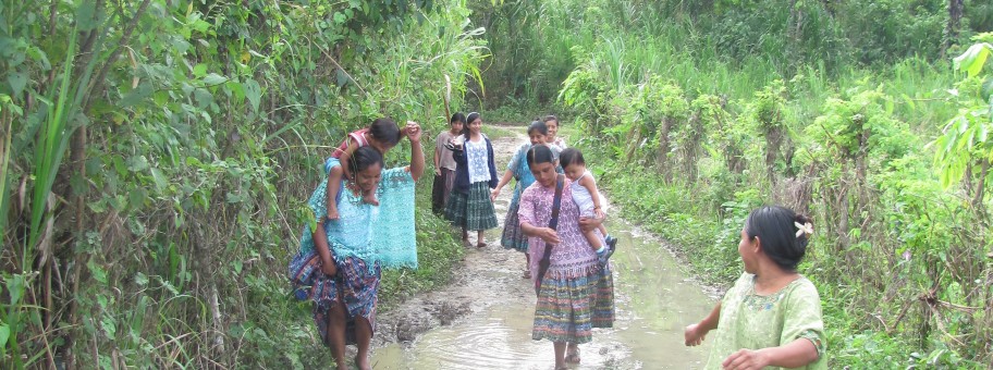 Mayan women walking down a muddy path