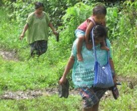 Mayan Q'eqchi woman carrying son down path