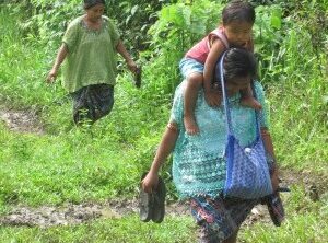 Mayan Q'eqchi woman carrying son down path