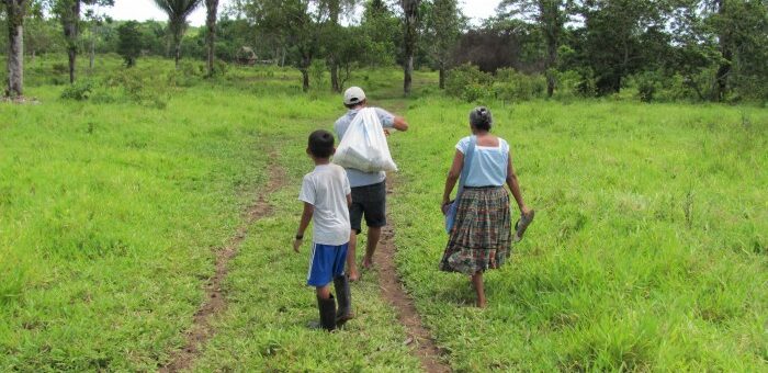 Family walking down muddy path to village